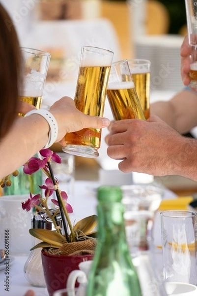 Fototapeta People who toast each other with beer glasses in their hands, cheers