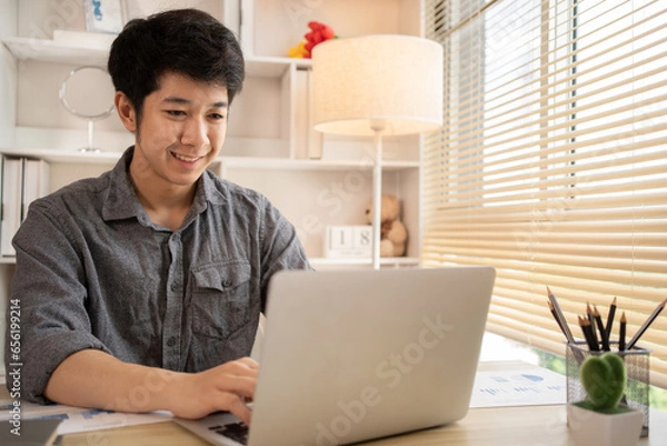 Fototapeta Man sat typing away on a laptop in his office with a determined look on his face, Work from the comfort of home, Male hand pressing on laptop keyboard, Work from home.