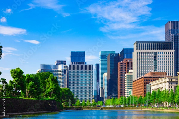 Obraz 皇居のお濠の池越しに見る日比谷通りと歩道の街路樹。日比谷、丸の内、大手町の高層ビル群（東京都千代田区）
