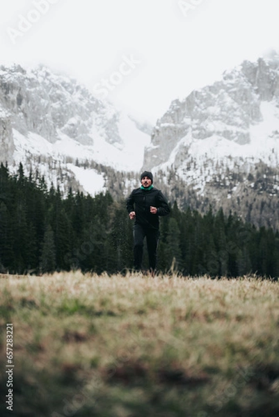 Obraz Hombre corriendo en llano con montaña nevada de fondo en Dolomitas.