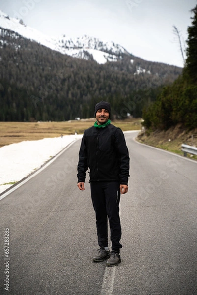 Fototapeta Hombre con gorro  en una carretera en Dolomitas con  montañas con nieve . 