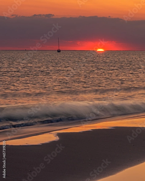 Obraz Sunset with orange sky and reflection on the beach and rings. Mediterranean, Camargue, Gard, France.