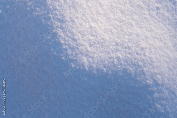 Fototapeta Hilly snow surface close-up in sunny day. Beautiful light and shadow pattern. Natural winter texture background. Copy space, top view.