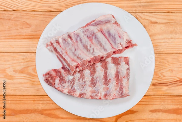 Obraz Raw pork ribs on white dish, top view