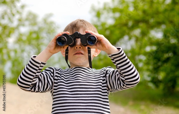 Fototapeta Little boy scanning the woods with binoculars