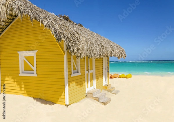 Obraz Wooden yellow hut on the beach covered with thatch and kayaks