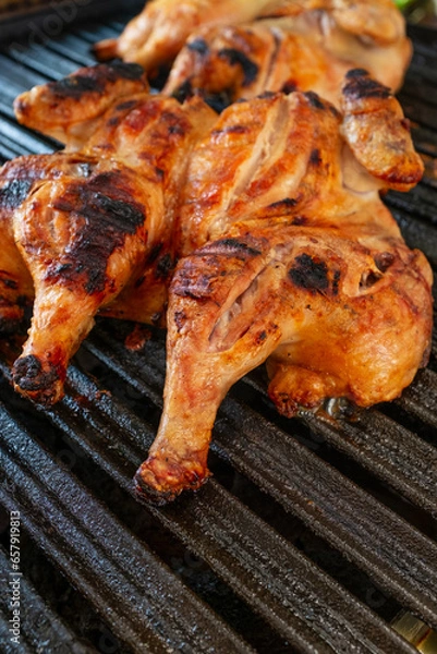Fototapeta Grilled Whole Chickens on Barbecue Grill with Focus on Foreground Drumstick