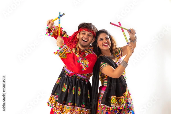 Fototapeta Portrait of happy young couple performing Dandiya Raas over white background