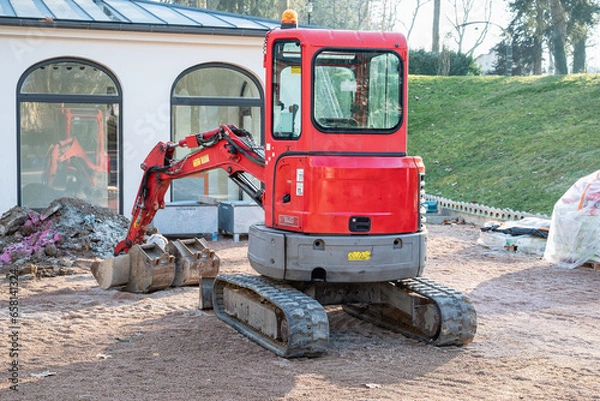 Obraz Small red excavator. Construction excavator in a construction site.
