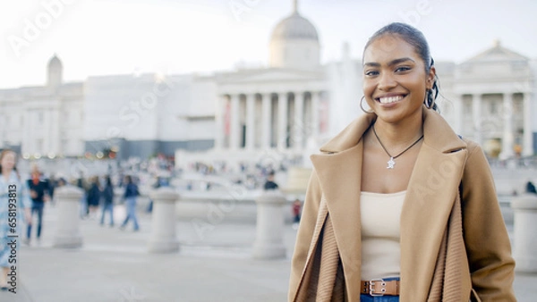 Fototapeta Portrait of attractive young female standing in the city looking to camera with a happy smile