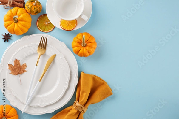 Fototapeta Arrange a Thanksgiving table that's truly memorable. Top view photo of plates, cutlery, cup, napkin, colorful pumpkins, orange, fallen leaves, anise, cinnamon on light blue background with advert area