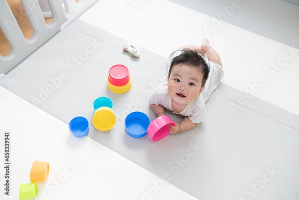 Fototapeta 自然光が入るリビングのプレイマットで知育おもちゃを使って遊ぶご機嫌笑顔な生後8か月の赤ちゃん