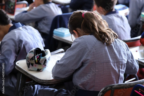 Fototapeta Students doing homework in the classroom. Boys and girls in classes. Primary school students in classes. Students in class at a Catholic school. Education. Children learning at school.