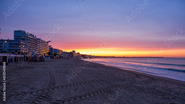 Fototapeta Amazing view of a fiery sunrise with multicolored clouds. Sea waves along the seashore at sunrise. Morning time. Ocean view. La Baule-Escoublac, France