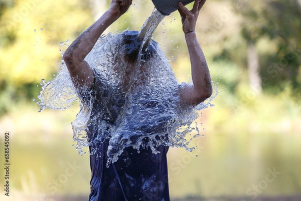 Fototapeta A man pouring bucket of water on his head as an element in obstacle race