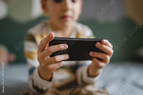 Fototapeta One caucasian boy child use smartphone mobile phone at home play games