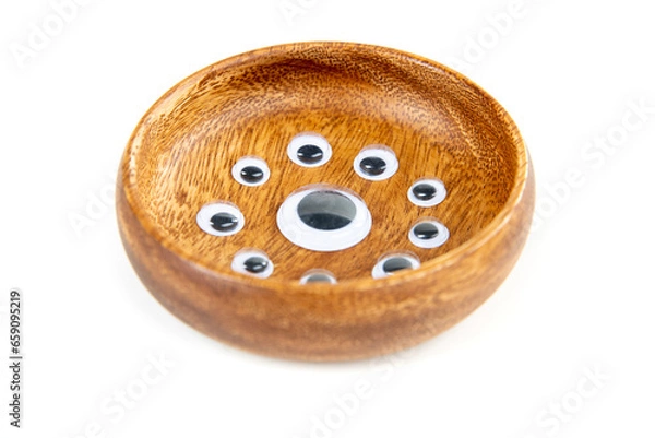 Obraz Small googley eyes surround a large single eye in a wooden bowl side view