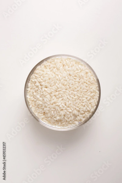 Fototapeta white rice in round glass bowl top view on white background