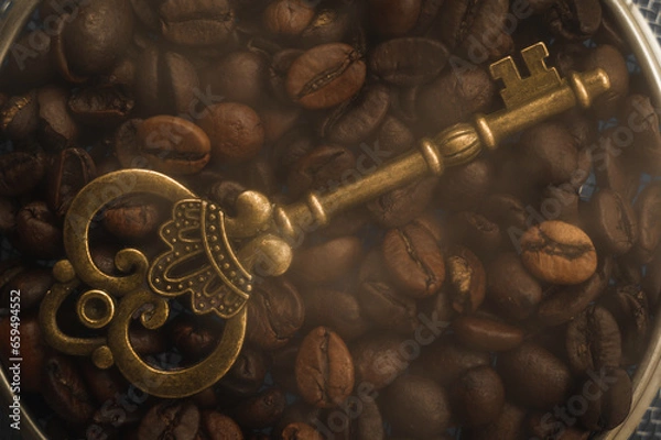 Obraz Golden vintage key on a background of hot coffee beans. An antique key against a background of coffee beans with smoke.