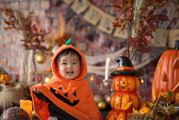 Fototapeta 10月にハロウィンのフォトセットに囲まれて楽しそうな笑顔を見せる生後11か月の赤ちゃん