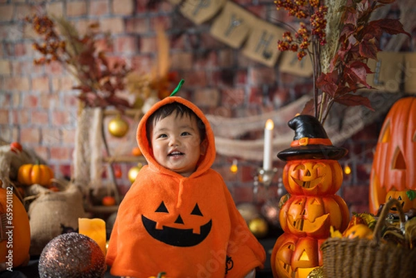Fototapeta 10月にハロウィンのフォトセットに囲まれて楽しそうな笑顔を見せる生後11か月の赤ちゃん