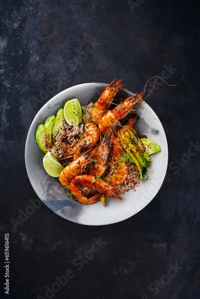Obraz Traditional Thai fried king prawns with Asian vegetable, avocado slices and rice served as top view on a design plate with text space
