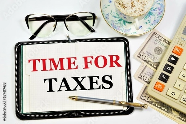 Fototapeta Time for taxes. An inscription in a planning notebook, against the background of cash and a calculator for calculations