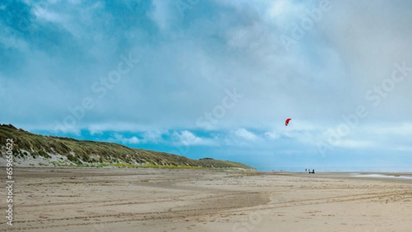 Obraz Walking on the beach at low tide in winter. A Kitesurfing wing in the sky. Coastline of Upper Normandy, France