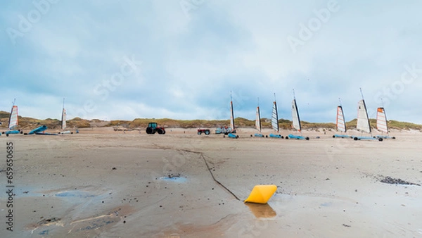 Obraz Storage of sand yachts on a beach at low tide. In winter between coast and sand a yellow buoy in the foreground. Coastline of Upper Normandy, France