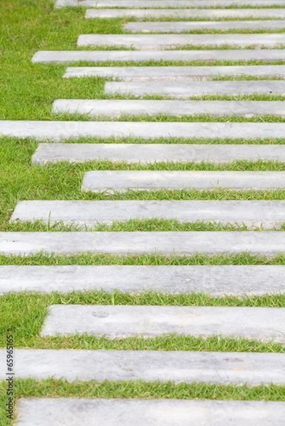 Fototapeta The Stone block walk path in the park with green grass