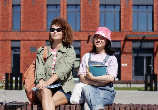 Fototapeta Waist up portrait of two smiling girls enjoying sunlight outdoors on college campus, copy space