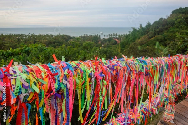 Fototapeta Arraial Dajuda, Bahia, Brazil: colorful souvenir ribbons hanging on the railing, sea on background