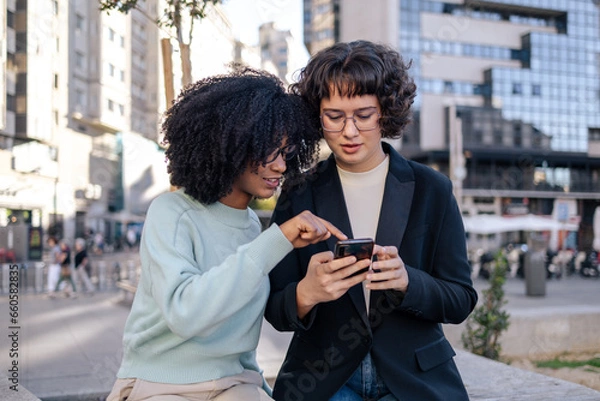 Obraz Two friends looking at smartphone in the street