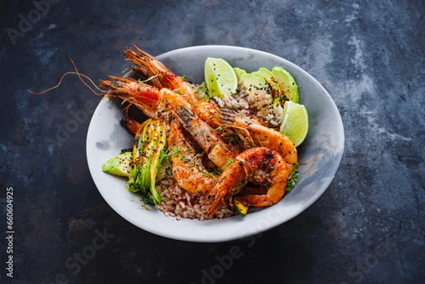 Obraz Traditional Thai fried king prawns with Asian vegetable, avocado slices and rice served as close-up on a design plate with text space