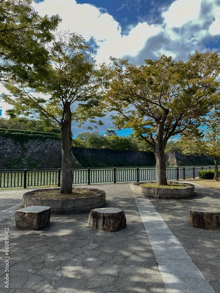 Obraz Promenade and trails inside public park in Japanese city of Osaka with modern architecture skyline cityscape view and historic fortress nature landscape scenery lots of trees, plants and bushes autumn