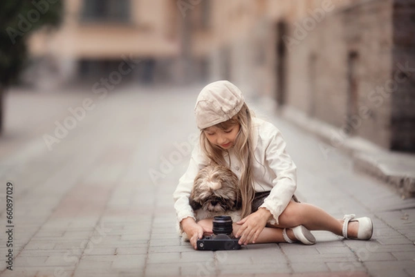 Fototapeta Little girl with camera and puppy taking photos on the streets of the city 