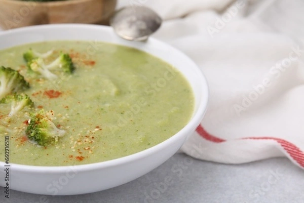 Fototapeta Delicious broccoli cream soup served on light table, closeup. Space for text