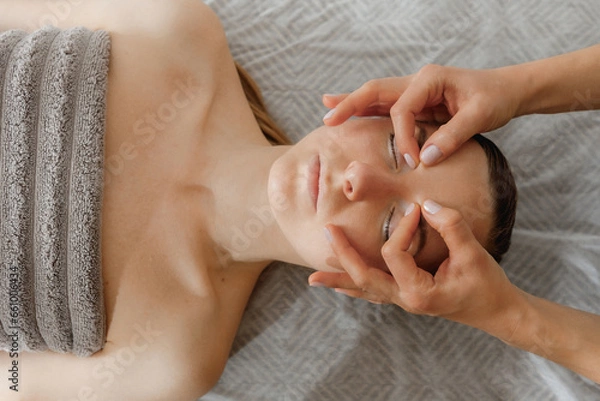 Fototapeta buccal facial massage, close-up, cosmetologist makes woman a procedure on a massage table in a spa salon