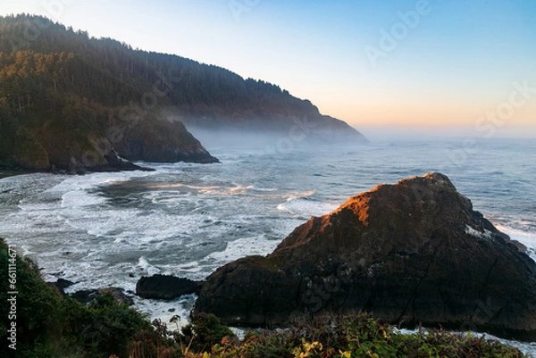 Fototapeta Sun peaking through at dawn on the magnificent Oregon Coast near Heceta Lighthouse.