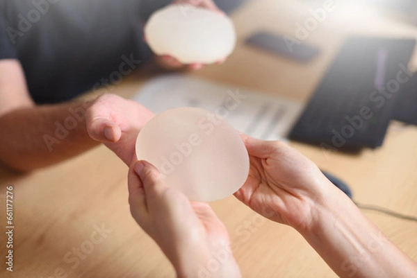Obraz Doctor offers breast augmentation implants to a woman