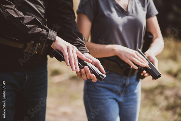 Obraz A weapons instructor teaches a girl to shoot a pistol at a firing range