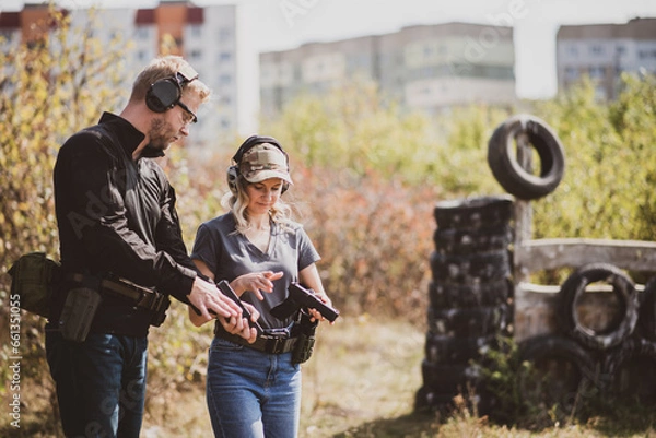 Obraz A girl learns to shoot a pistol at a shooting range with an instructor