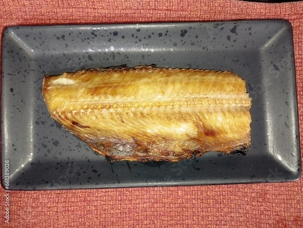 Obraz 焼き魚ホッケが黒い皿の上にのっている