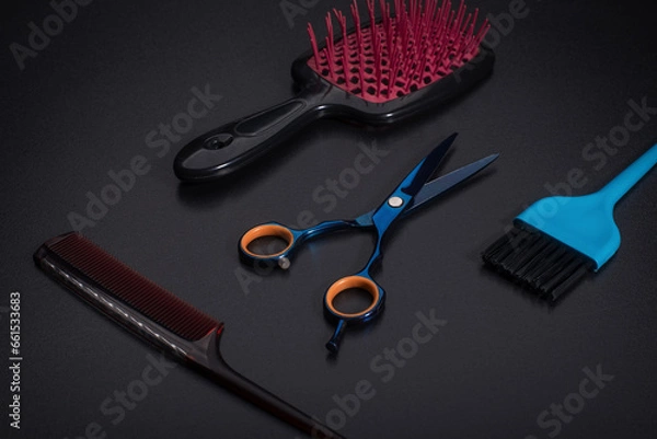 Obraz Hairdressing tools on a black background. A hair massager or comb next to the scissors.