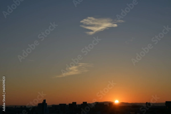 Fototapeta 都市の夜明け。日の出とともに空と雲がオレンジ色に染まり、ビル群はシルエットとして写す。神戸市東灘区から大阪方面をのぞむ