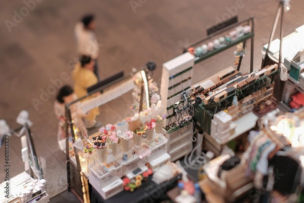 Fototapeta High angle view of customers at indoor festive weekend market. Social pop up event in shopping mall for entrepreneurs and makers. Captured with a tilt-shift lens. Selective focus; bokeh effect