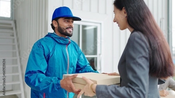 Obraz Woman manager taking pizza box from food delivery man for enjoy lunch together with colleagues in meeting room at office.Women manager orders food online to team. Delivery food concept