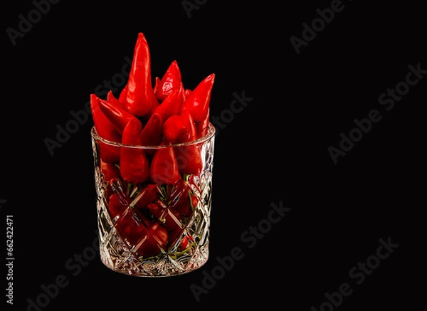 Fototapeta A glass full of red hot peppers on a dark background.