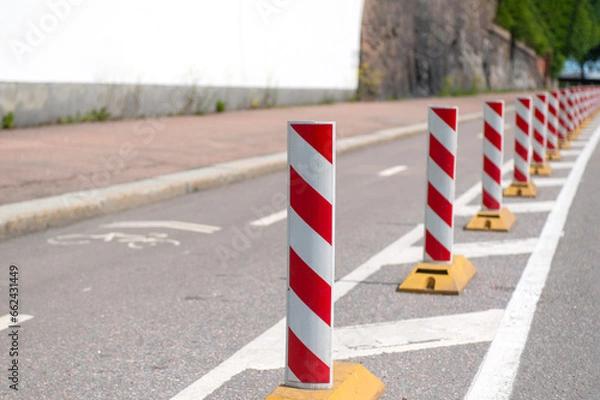 Obraz a row of light reflective red-white posts on the road, duplicating the markings separating the roadway from the bike path. Sunny summer day