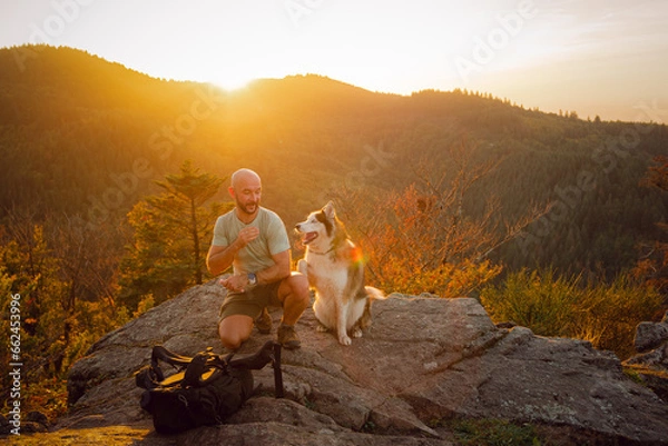 Fototapeta The man and best friend dog husky enjoy the time in a sunset on the mountain. 